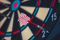A dart striking the bullseye on a dartboard, showcasing precision and accuracy.